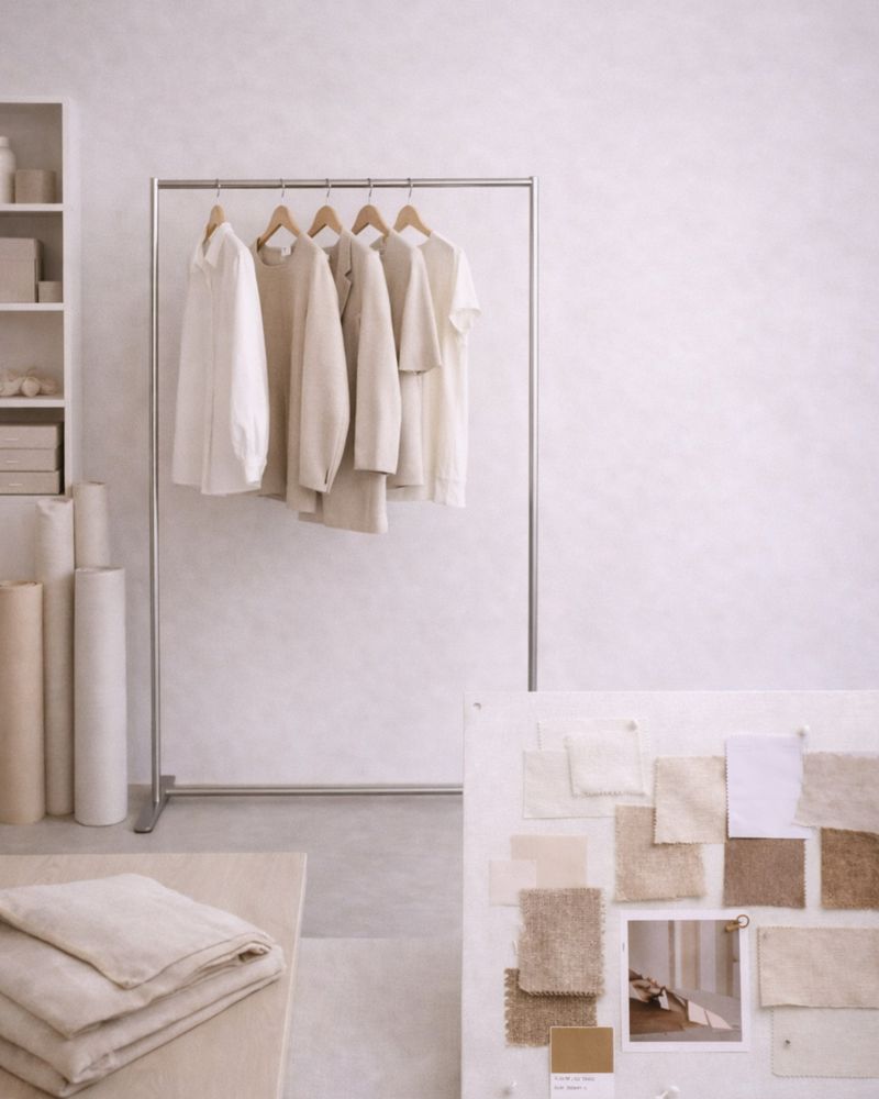 Clothes rail with light garments and contrasting fabric swatches on the floor