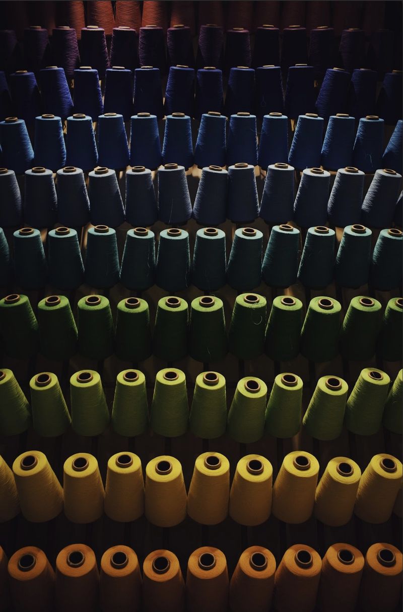Shelves of yarn cones arranged by colour range in a textile mill