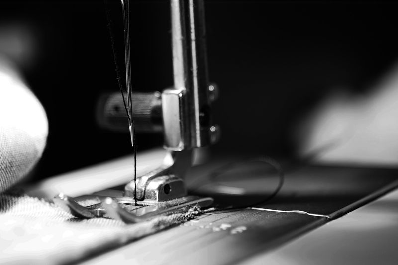 Sewing machine running, detail of needle and thread, in black and white
